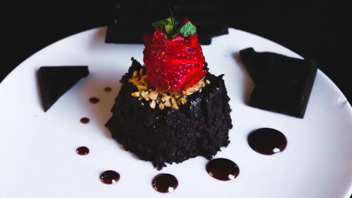 A luxury individual dessert. Dark chocolate sponge topped with a single raspberry.