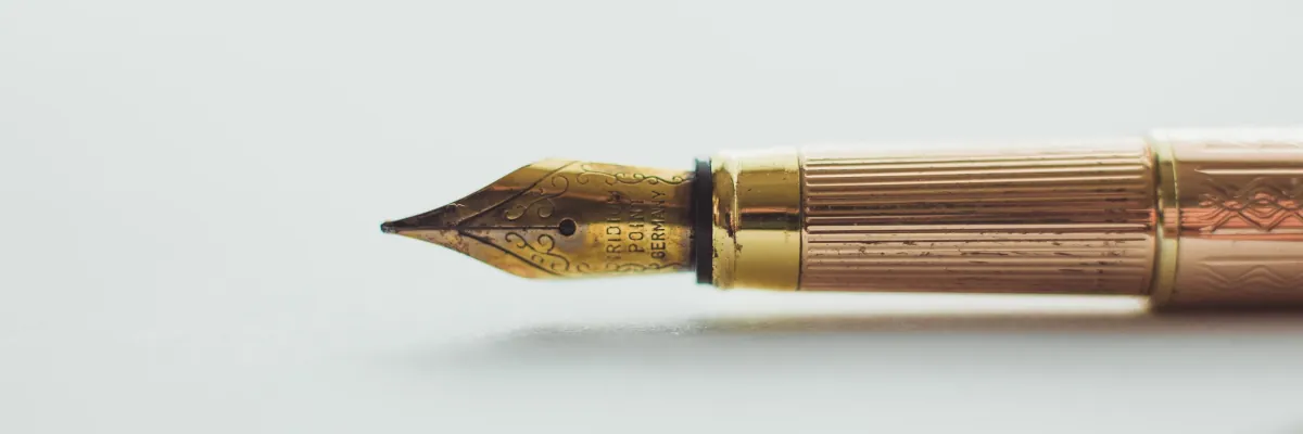 A header image of a gold coloured fountain pen lying horizontally on a plain background.